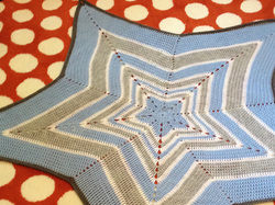 Photograph of a crocheted baby blanket in the shape of a star.